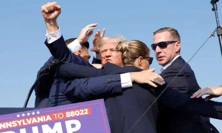 Donald Trump mengangkat tinjunya ke atas saat dalam pengamanan agen rahasia AS. foto: dok/bbc